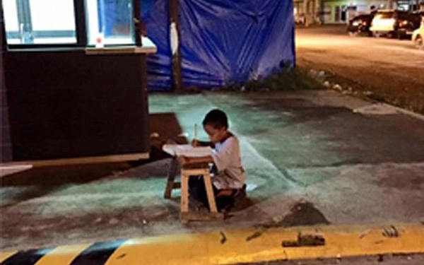 Cậu bé vô gia cư dùng ánh đèn lọt ra từ cửa hàng mcdonalds để học bài - 1
