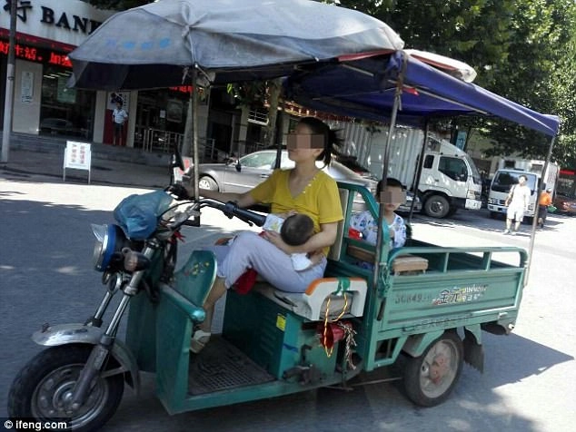 Bà mẹ gây tranh cãi khi vừa lái xe 3 bánh chở con phía sau vừa cho bé khác bú - 1